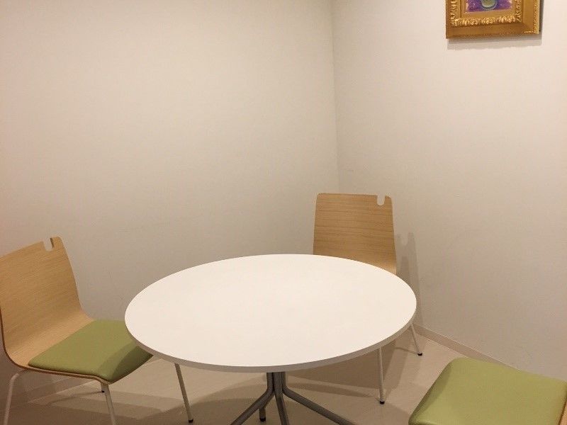 明るい雰囲気の相談室は白い壁で金の額に入れられた絵画が飾られている。丸いテーブルのセットもある。