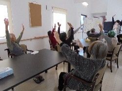 スタッフに習って手を挙げて体操に取り組む入居者の姿。