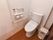 トイレの床はフローリングで右側にはゴミ箱が置かれ、左側の壁にはトイレットペーパー掛けが設置されている。