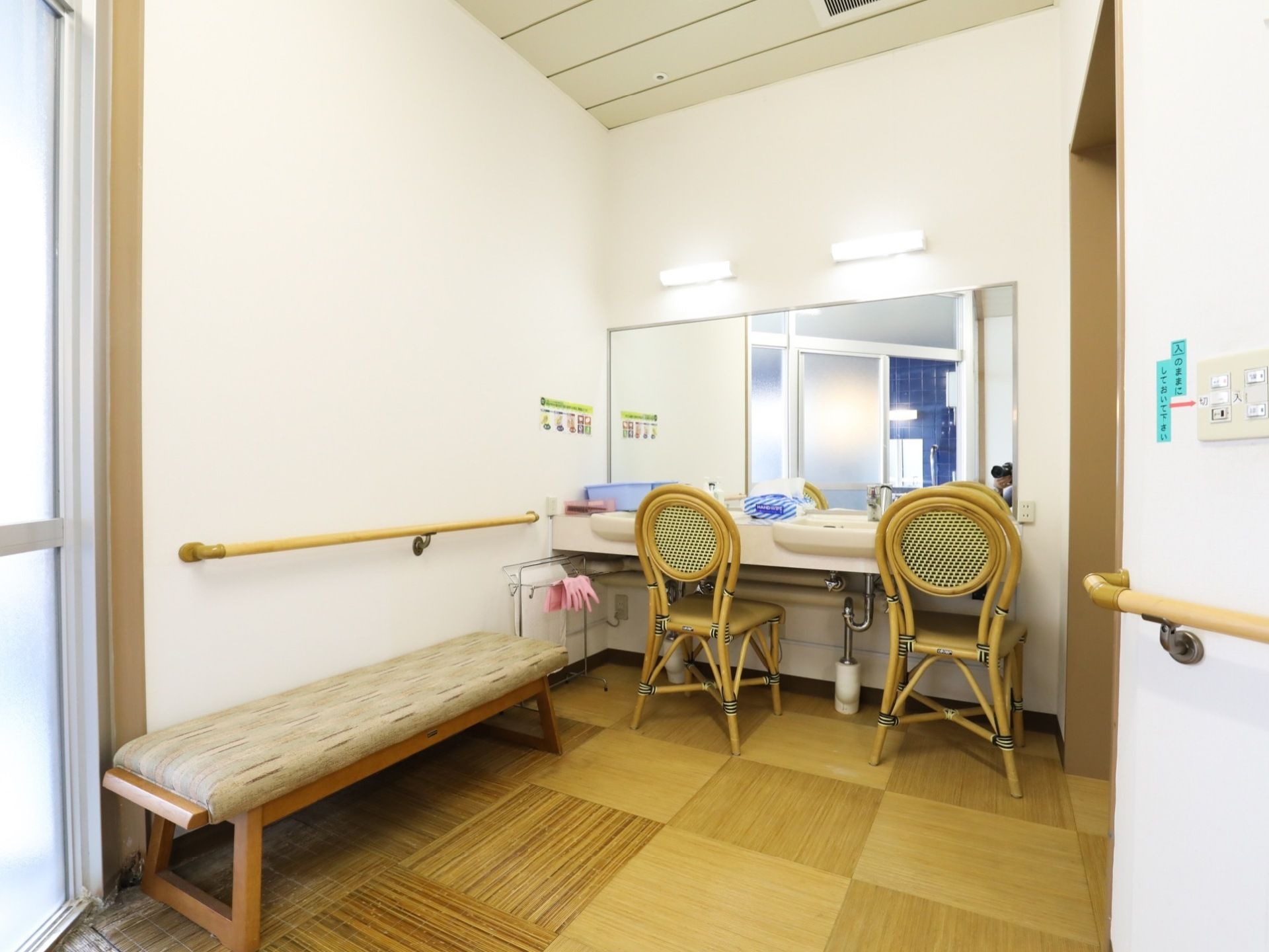 広々とした脱衣所には、壁に大きな鏡が取りつけられている。長椅子や１人掛けの椅子が２脚並べられている。