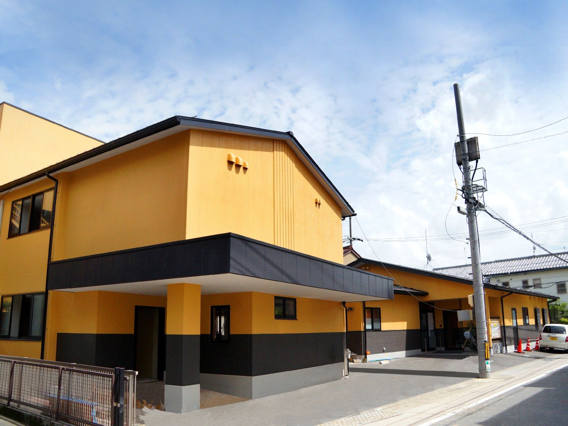 2階建ての建物の外壁は山吹色でフレッシュな印象。黒い屋根が建物全体を引き締めている。