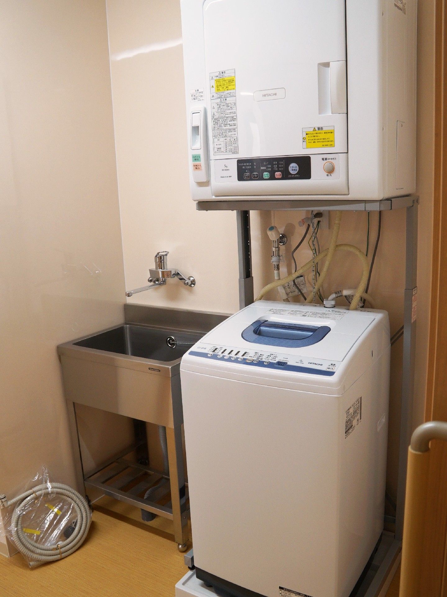 縦型洗濯機の上には乾燥機が設置され、横には手洗い場がある。