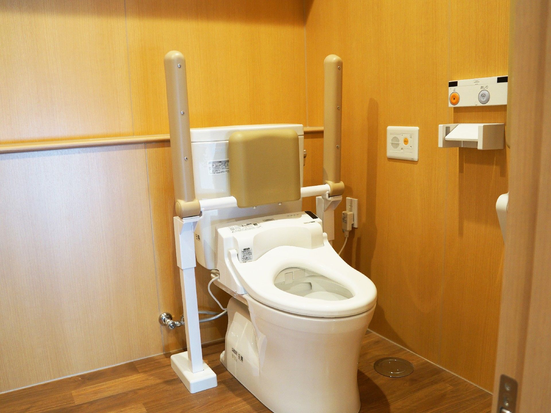 両サイドに可動式の手すりが付いたトイレは背もたれもつき安全に使用できる。