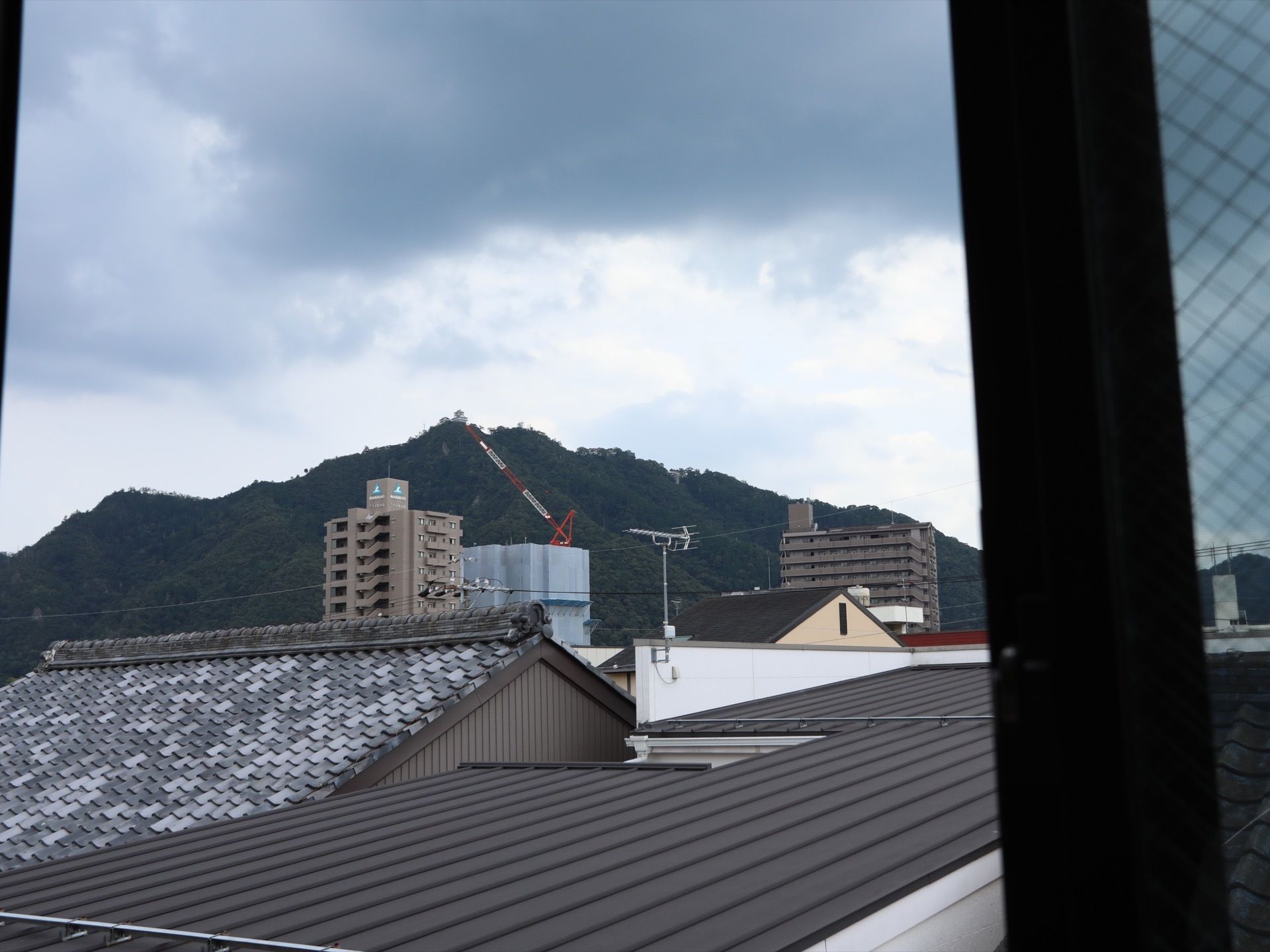 窓からは木々が茂る小高い丘を望むことができる。周辺は戸建ての住居が多く、高層の集合住宅もいくつか見える。