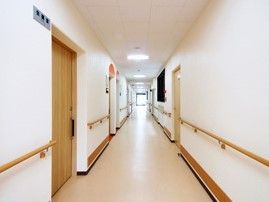廊下はまっすぐに伸びている。両サイドに手すりがあり、突き当たりのドアから日差しが入ってきて明るい雰囲気。