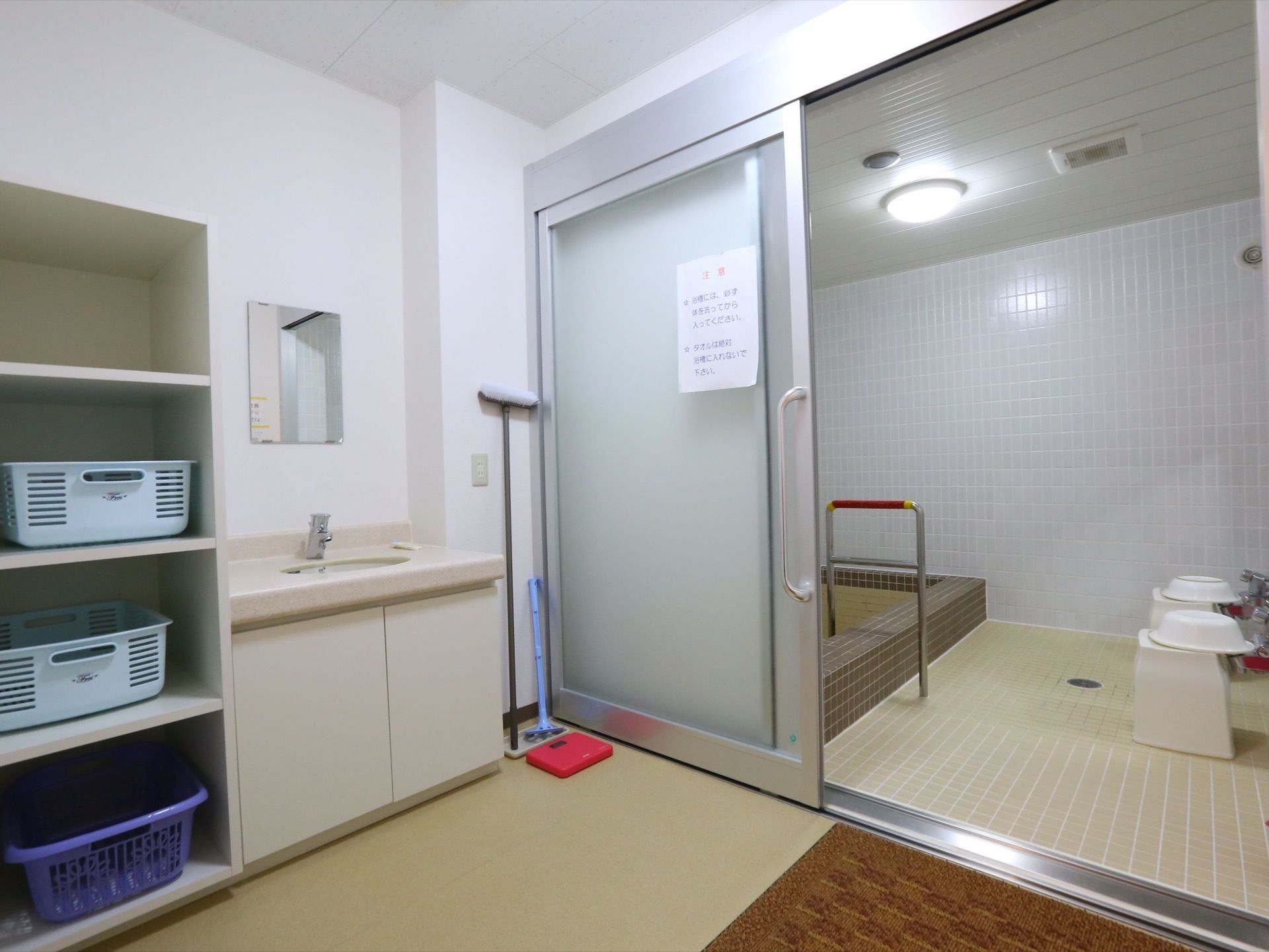 壁と床がタイル張りの、広々とした浴室である。出入口の扉は大きな引き戸になっている。脱衣所には洗面台や鏡も設置されている。
