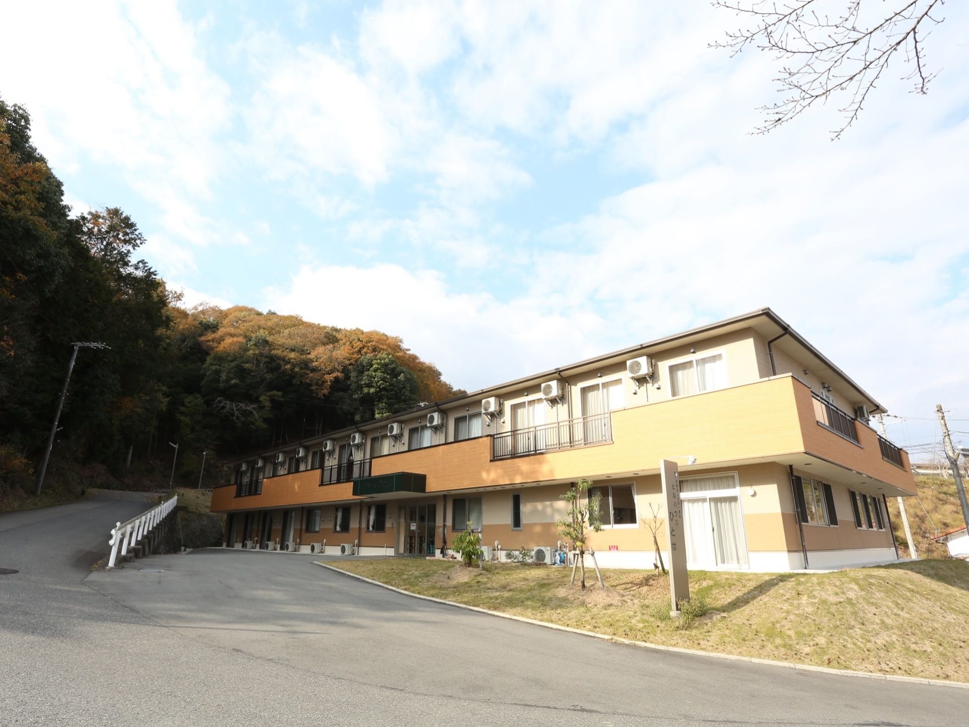 自然に囲まれた場所に建っている、オレンジの壁が特徴的な建物となっている。玄関のすぐそばに車を停めることが可能。