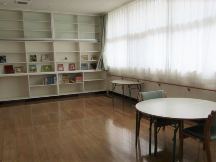 壁一面が白い本棚となっていて、窓は大きく明るい雰囲気。フローリングの床も掃除が行き届いている。