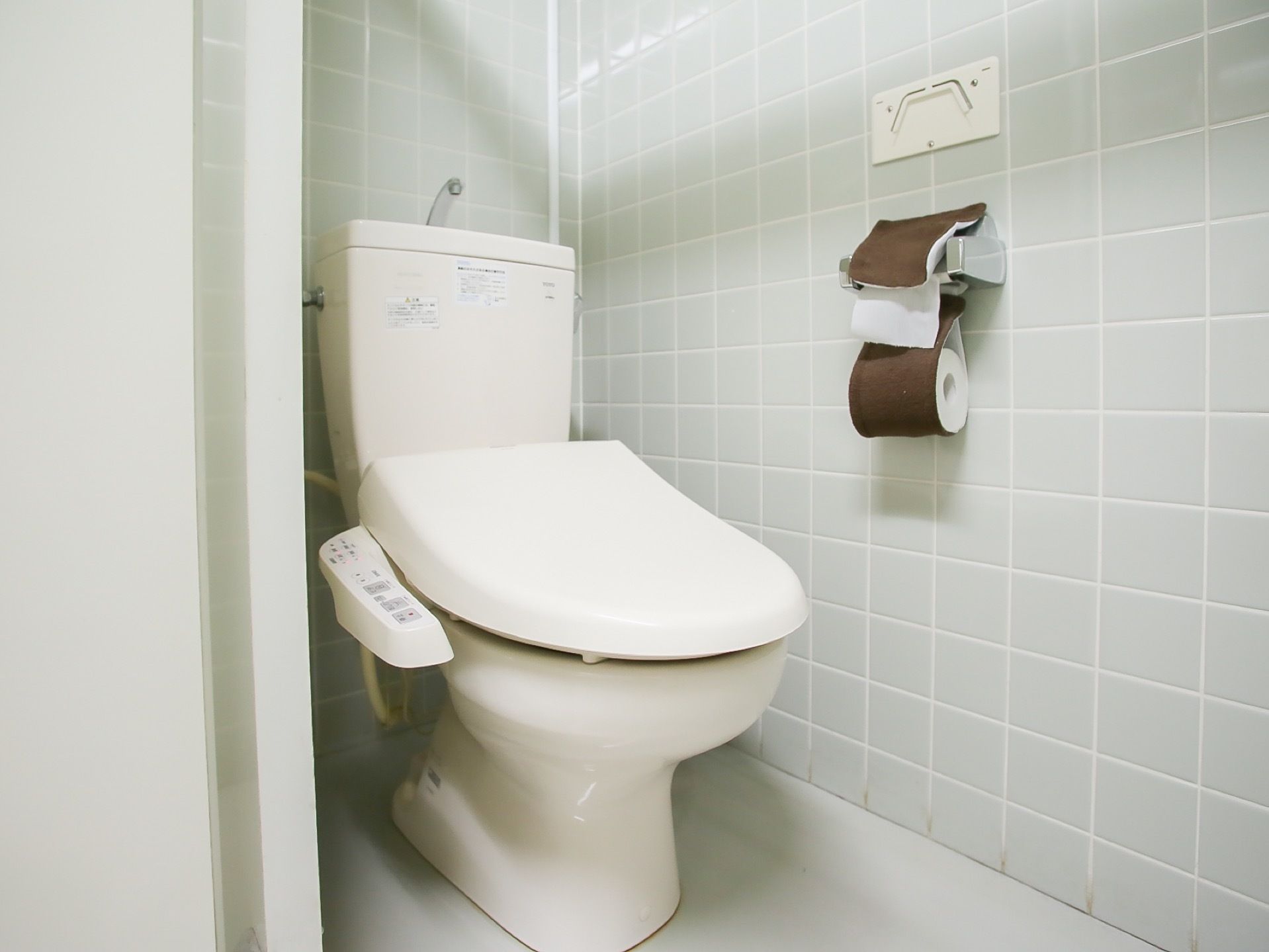 温水洗浄機能付きのシンプルな個室トイレである。壁はタイル張りとなっており、ペーパーホルダーが取りつけられている。