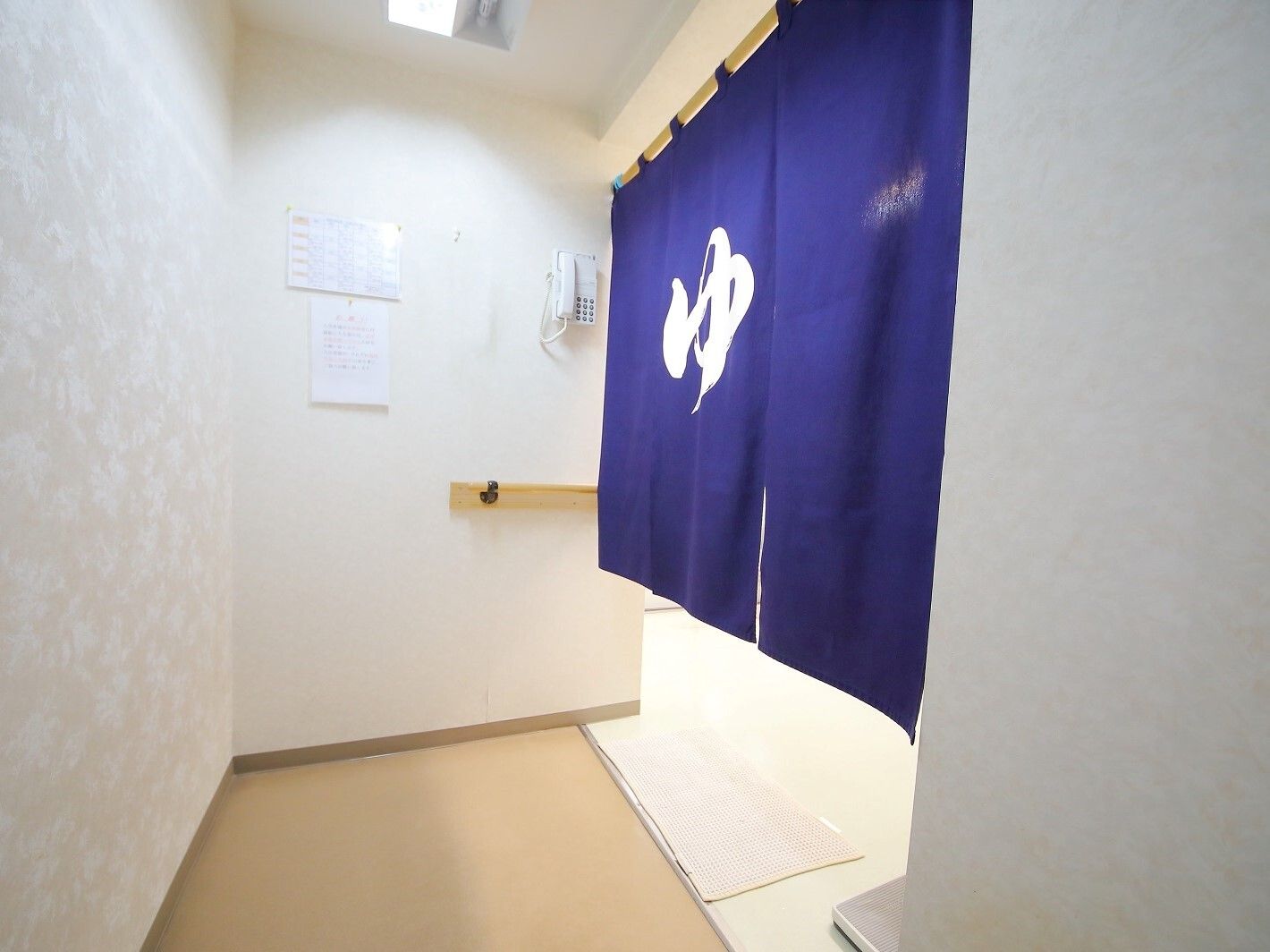 清潔感あふれる脱衣所で、洗面台下には椅子が収納されている。横の棚には、お洋服を入れるための木のカゴが複数用意されている。