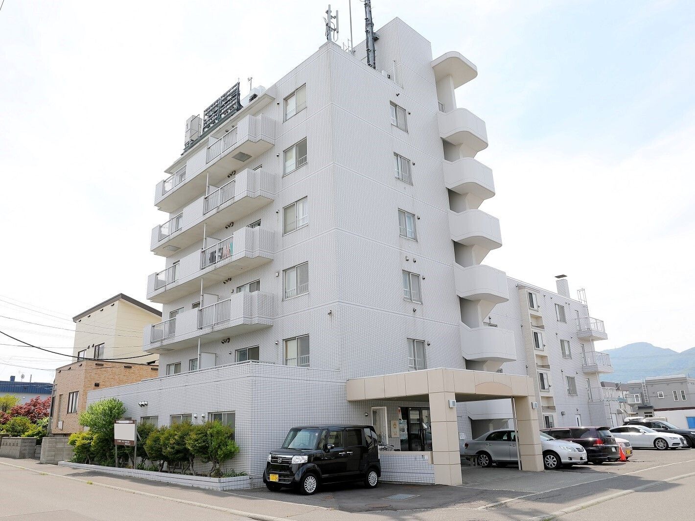 ４～６階建ての白いマンションのような造りの建物が当施設である。玄関前は大きなひさしがついており、駐車スペースも完備されている。