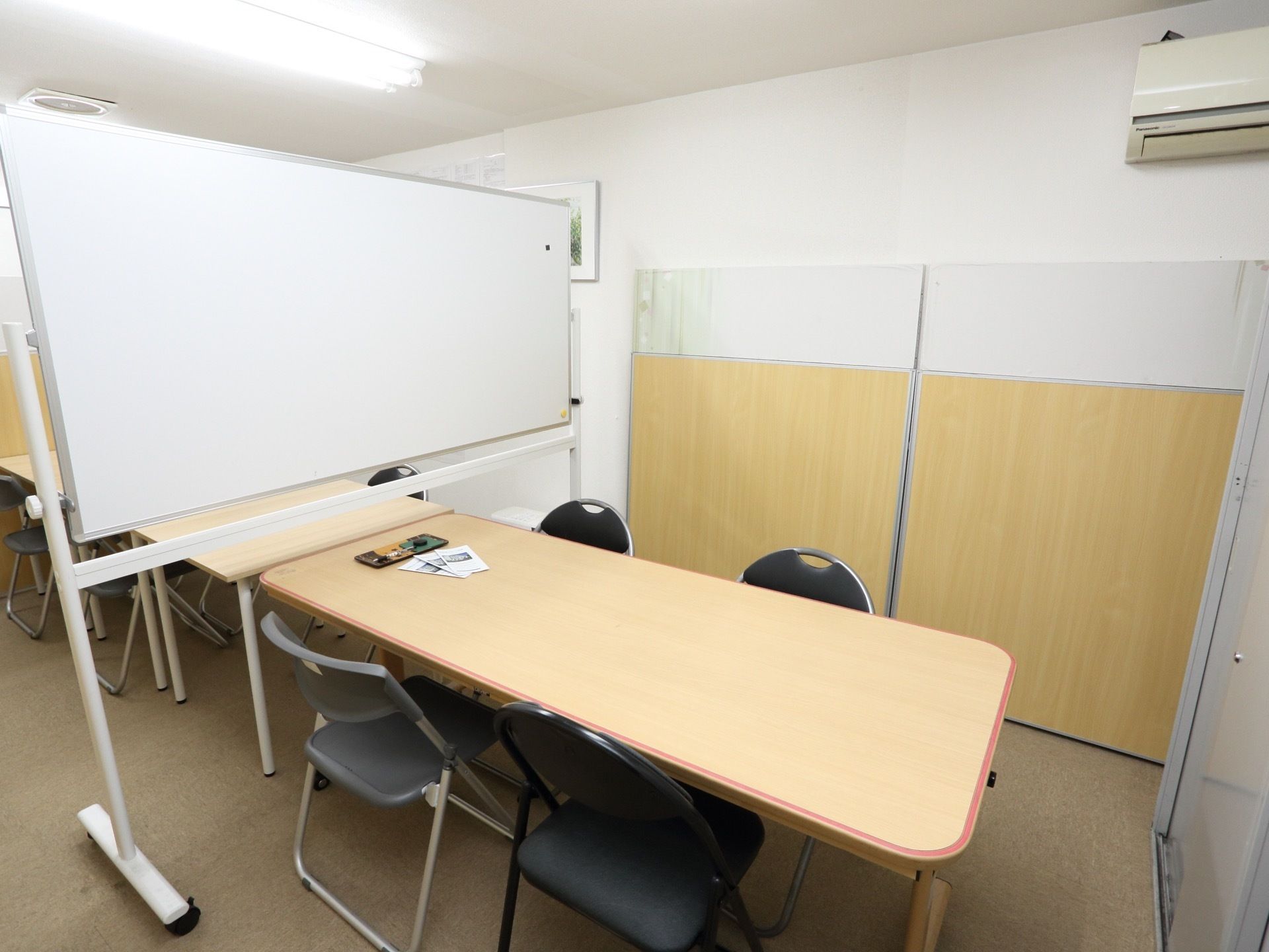 四人掛けの机と椅子が置かれている小部屋がある。中央にホワイトボードが置かれ、部屋を二つに区切られている。