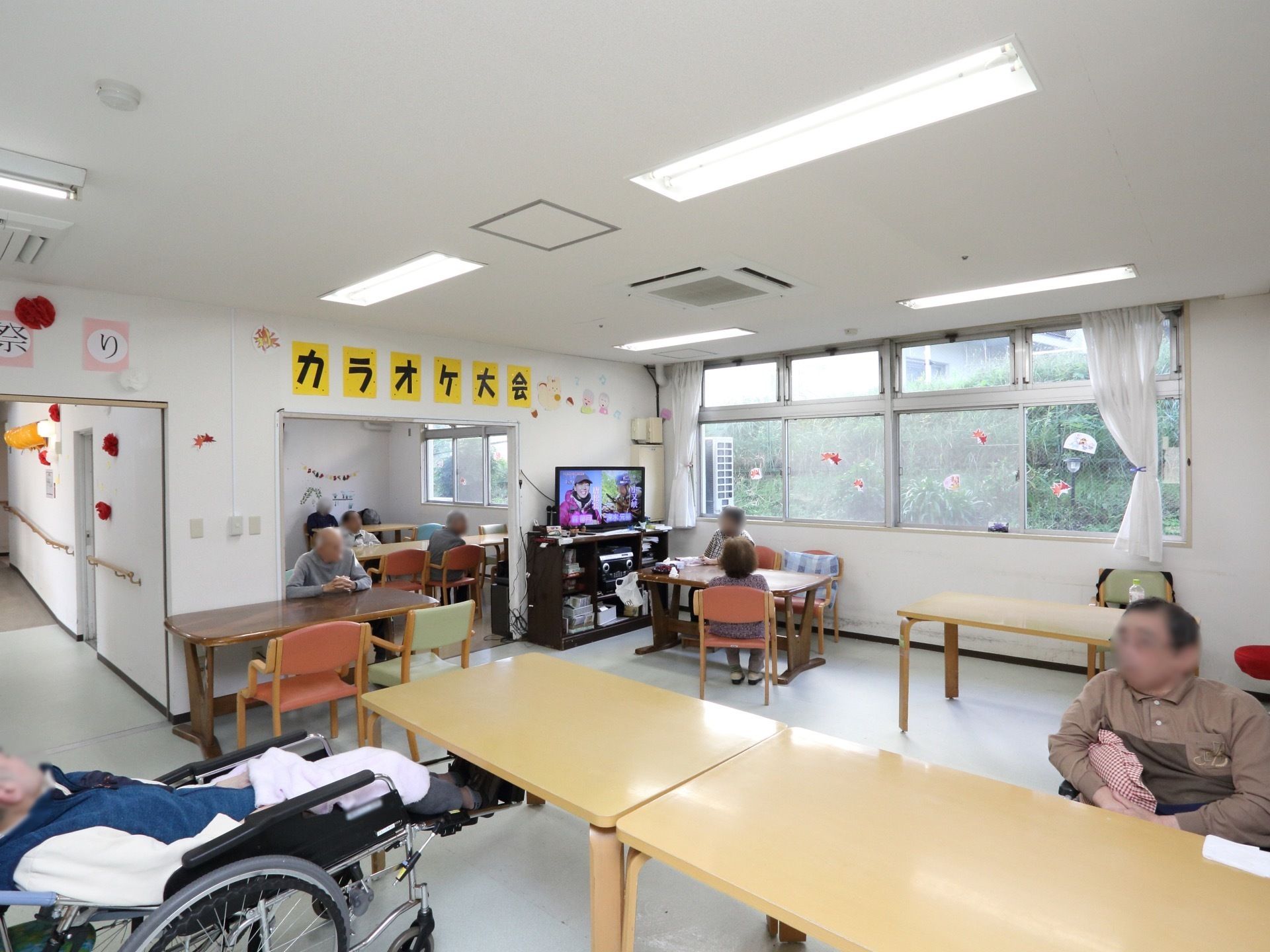 大きなテーブルと椅子が並んでいる広い食堂がある。壁際にはテレビが置かれている。奥にも部屋があり、同じように座席が設えてある。