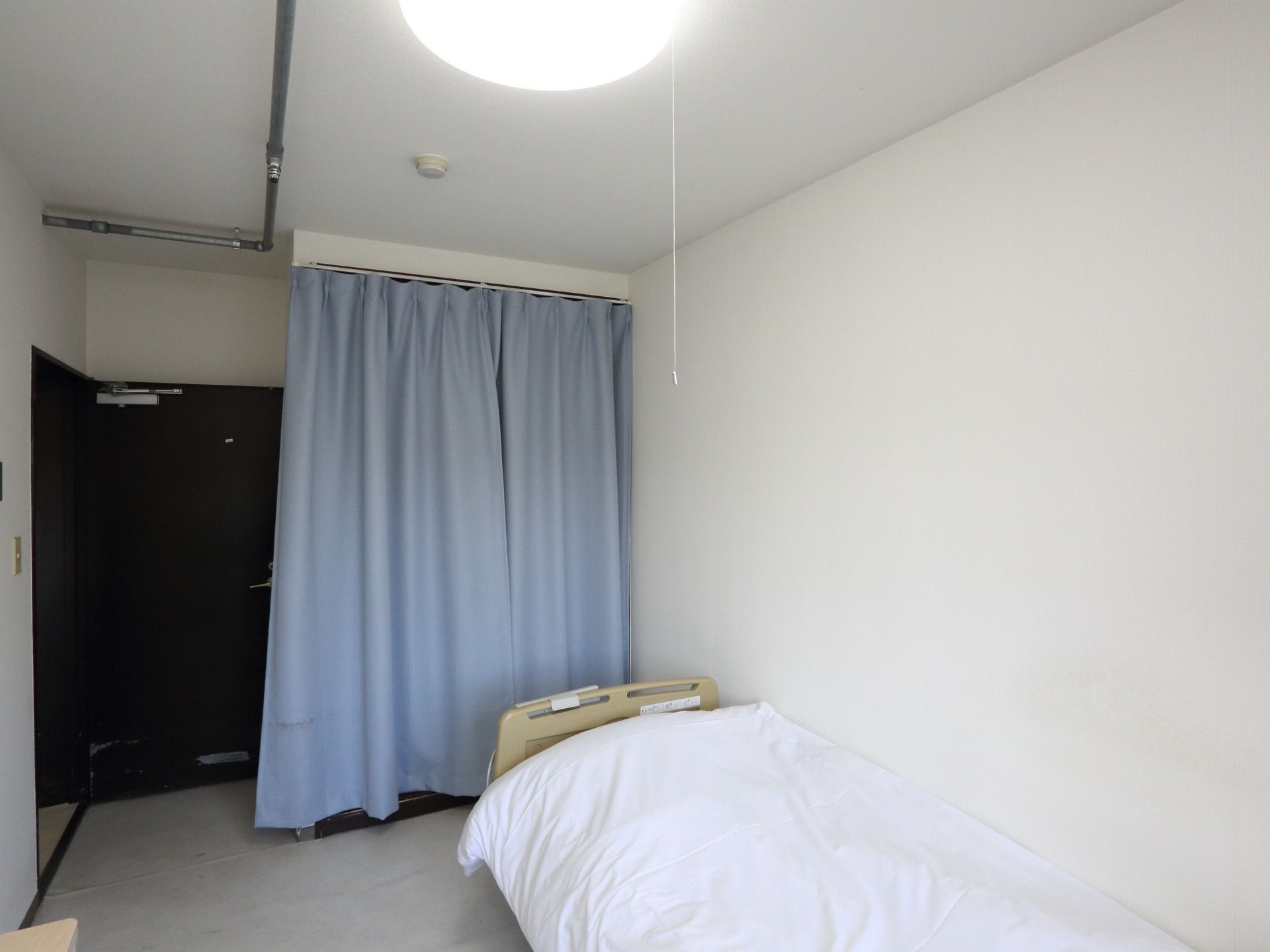 ドアとは反対側の壁にベッドを寄せて配置して、通路を広く確保して入居者様が生活しやすい同線作りがされている。