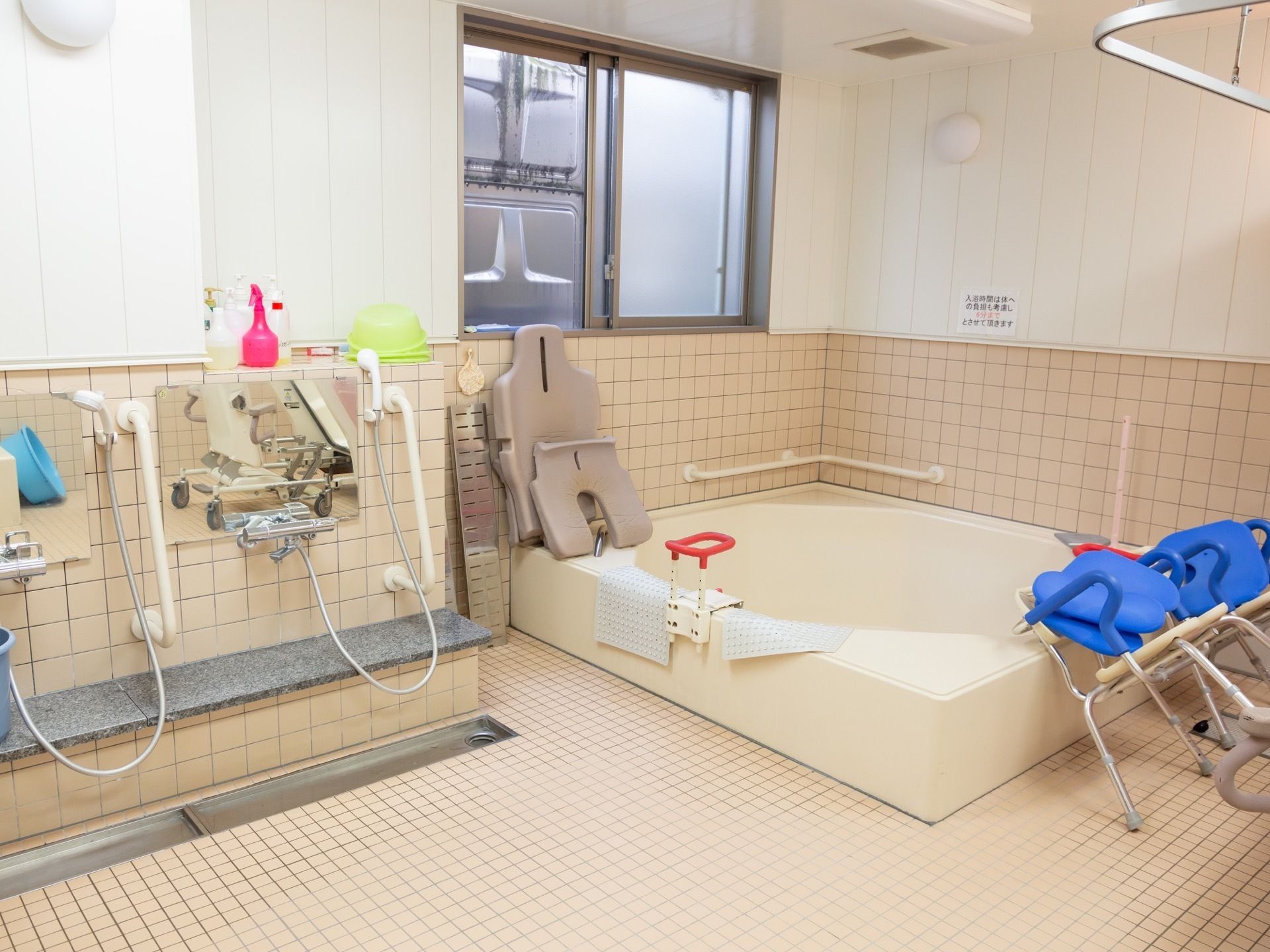 大人数で利用できる大浴場には、介護用の椅子が２脚用意されている。洗い場には手すりが取りつけられている。