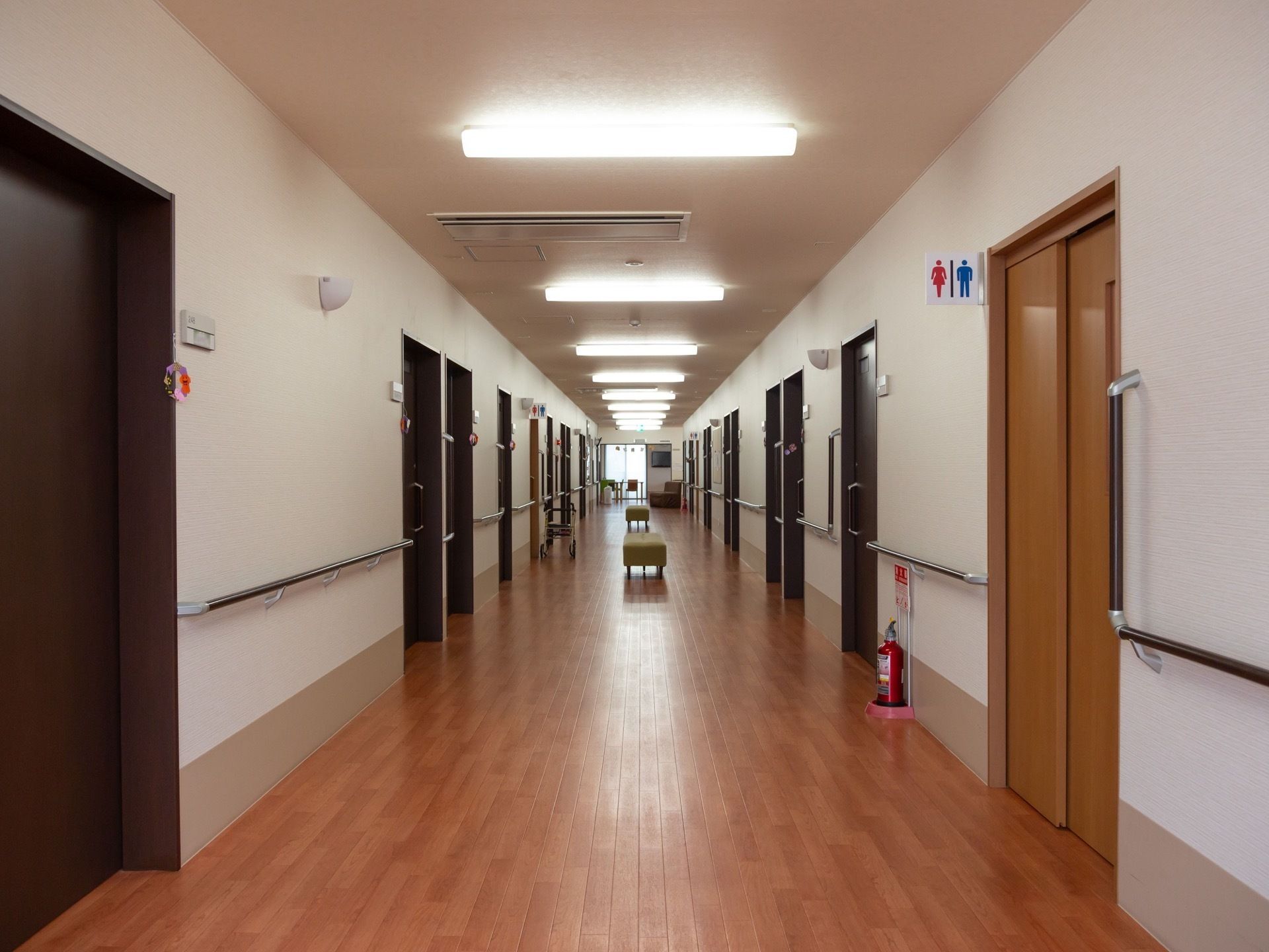 淡い色調の木目床に白い壁の通路である。壁に手すりが続いており、通路の中央部にいくつか椅子が置かれている。