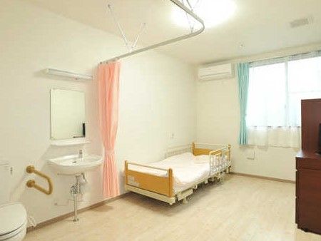 カーテンで仕切られたトイレ、洗面台がある部屋。ベッドやエアコンがある様子が分かる