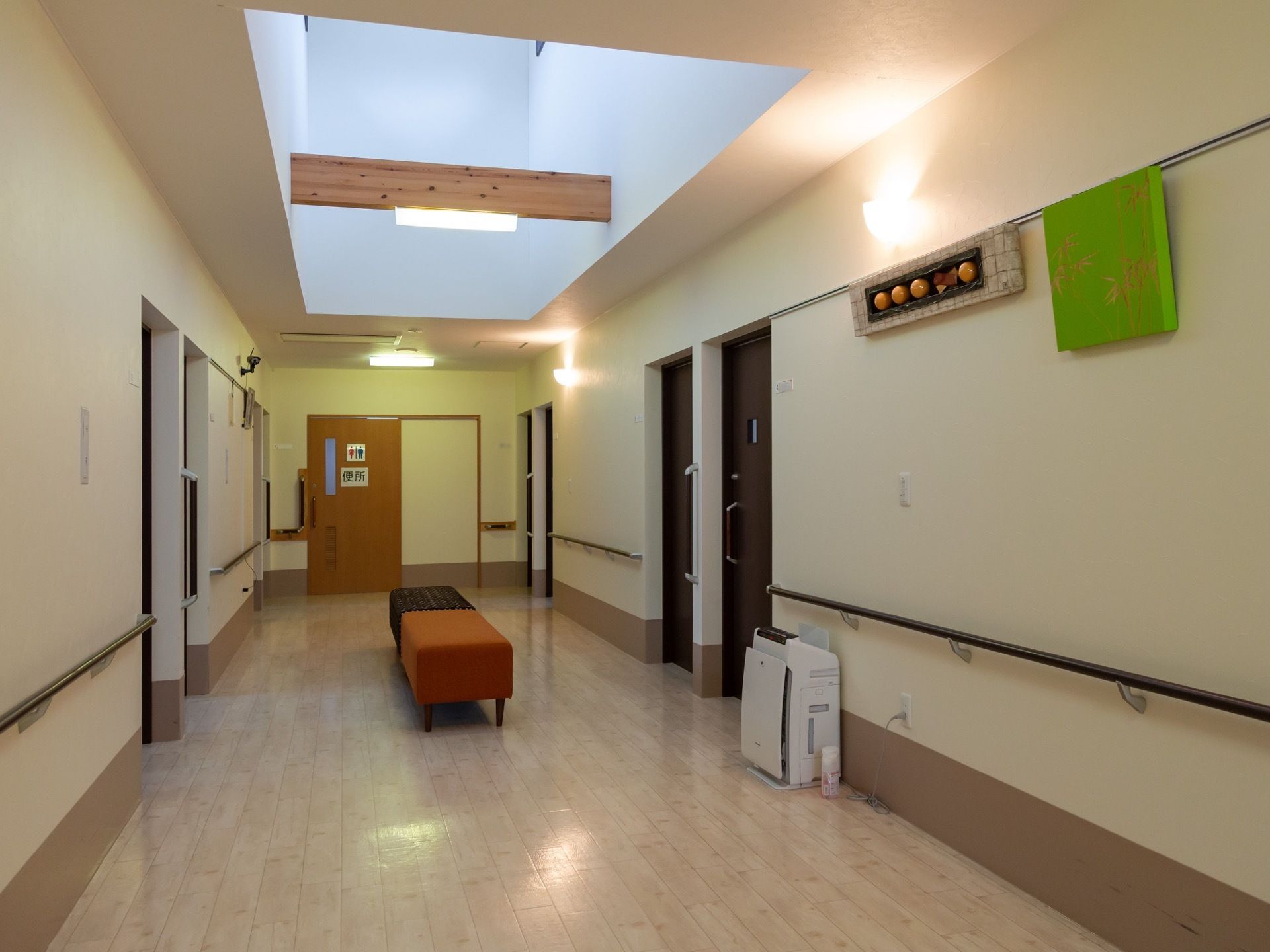 廊下の天井は吹き抜けになっている。 突き当りにトイレのドアがあり、貼り紙がされている。中央にベンチが置かれている。