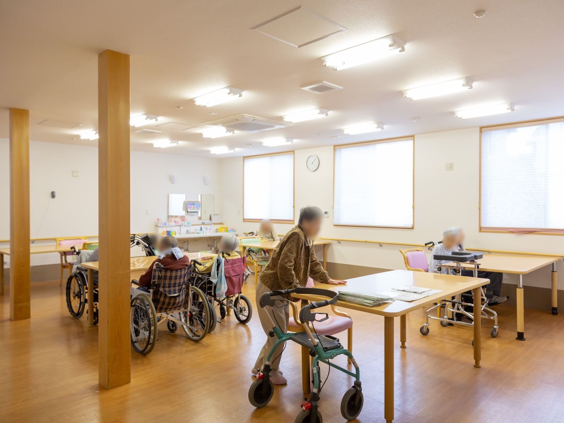 共有スペースでは入居者様が談話をしたり、のんびりとくつろいだりしている。広々とした室内には窓があり、明るく開放的である。