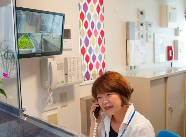 女性スタッフがスタッフルームで電話を受けている様子。白を基調としたスタッフルームは清潔感がある。