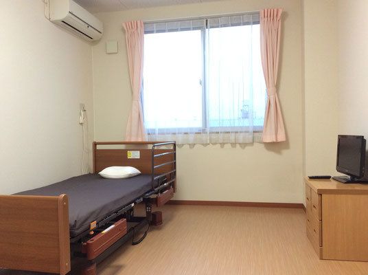 フローリングのシンプルな居室にはカーテンや収納、ベッドやエアコンが付いている。