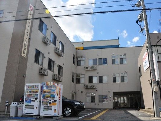 3階建ての建物。外壁にはホーム名が書かれ、駐車場もある。