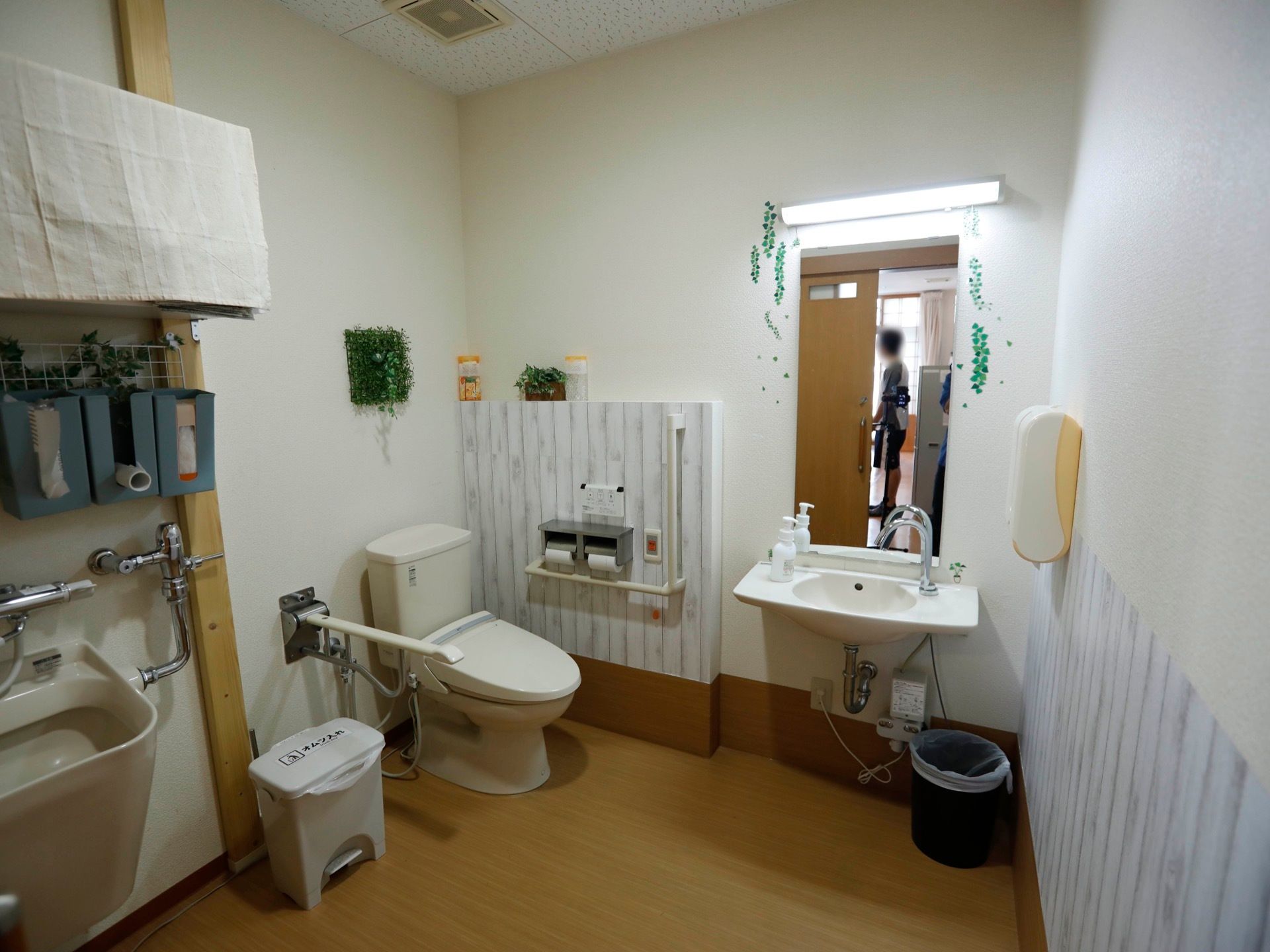 車椅子のまま入室できる、広いスペースを確保したトイレである。壁の一部に木目調のアクセントクロスが使われ、おしゃれな印象。