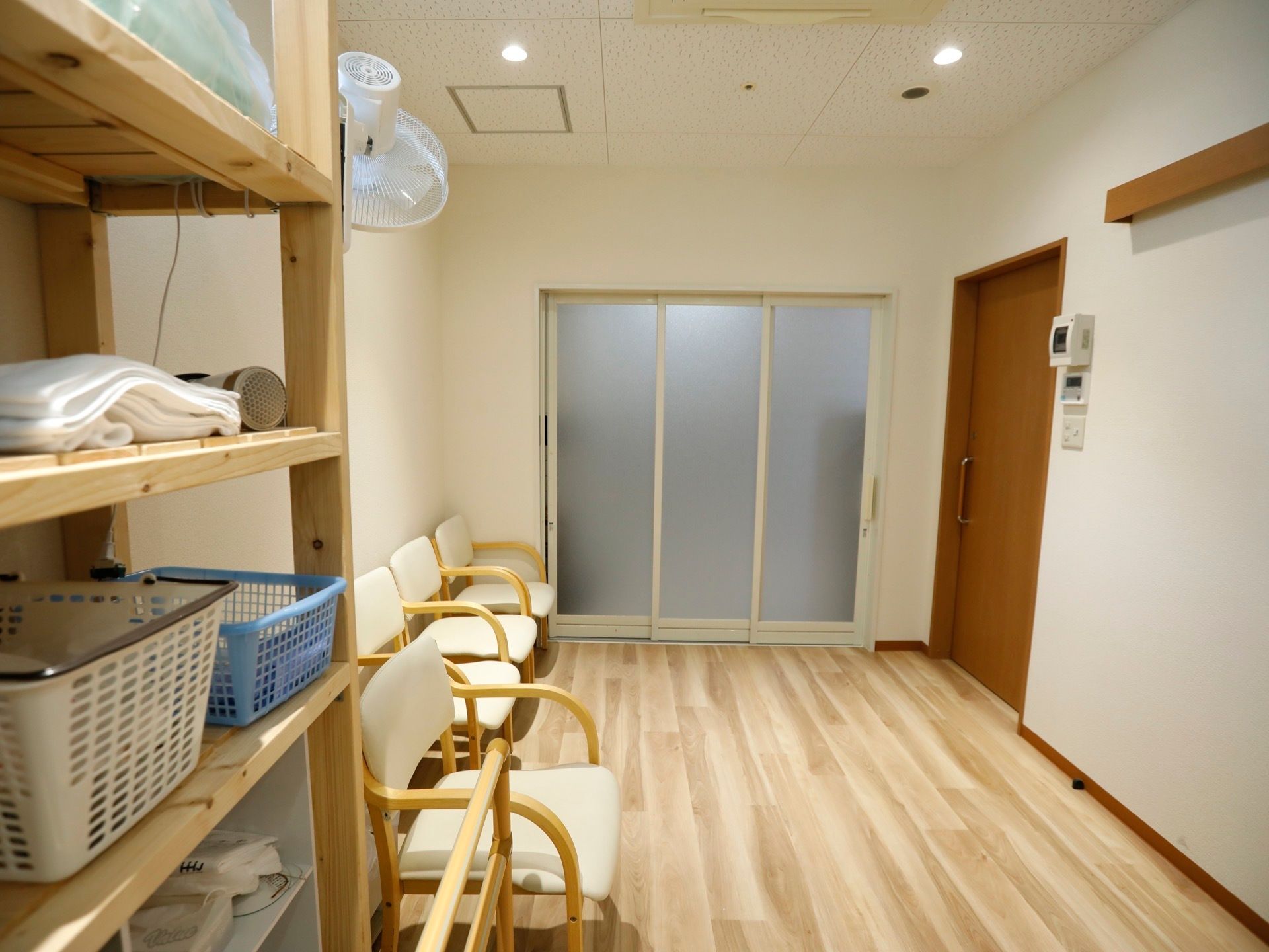 脱衣所の壁に寄せるように、椅子が多数並べられている。横には収納棚も設置され、真ん中は通路として広くスペースを空けている。