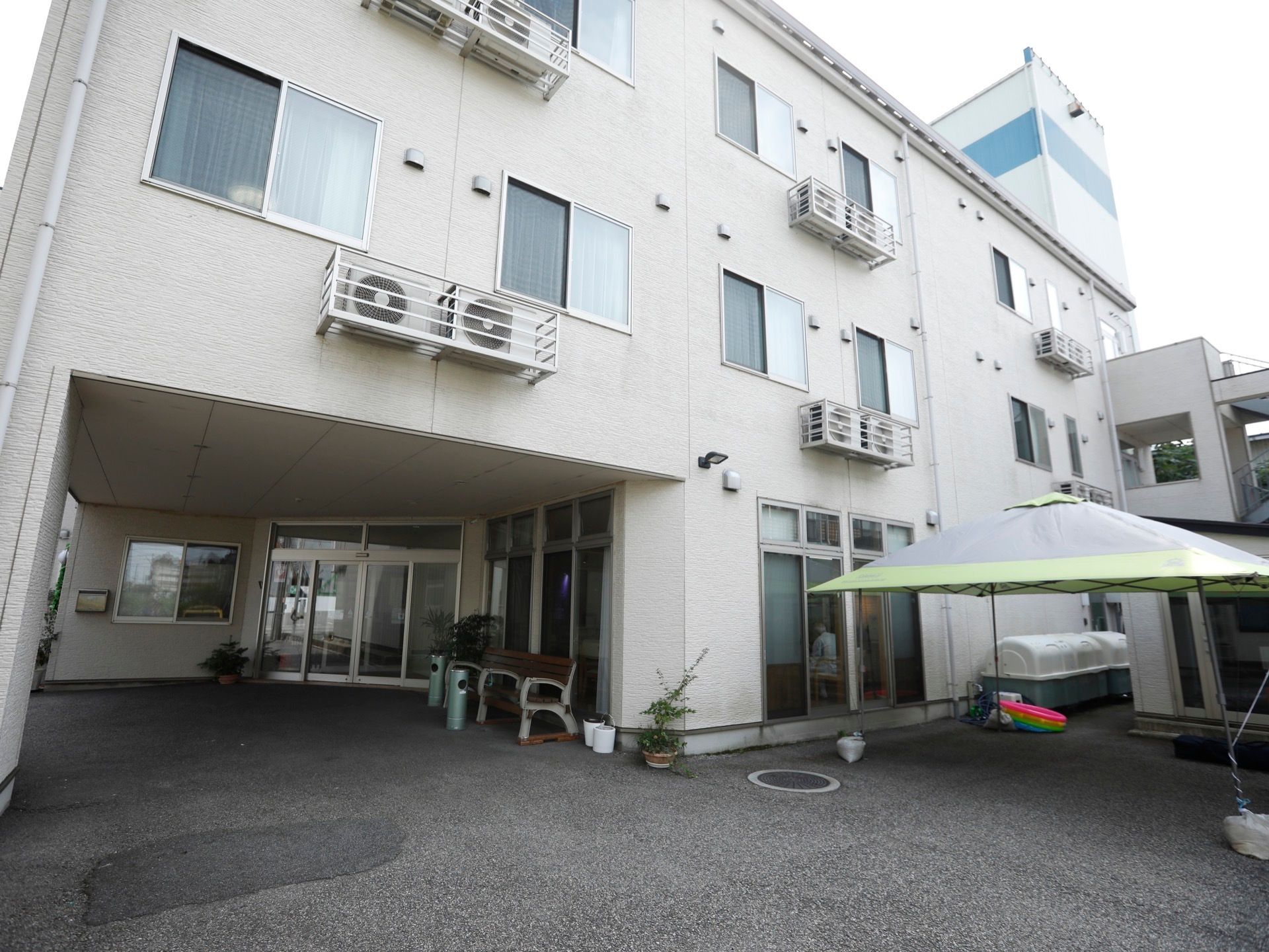 白っぽい色の、コンクリート造りの3階建ての建物である。建物脇には、黄緑色の屋根のテントが張ってある。