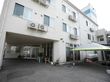 白っぽい色の、コンクリート造りの３階建ての建物である。建物脇には、黄緑色の屋根のテントが張ってある。
