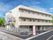 各フロアにベランダがあるベージュの外壁の建物。3階建ての建物の側面には屋外階段も付いている。