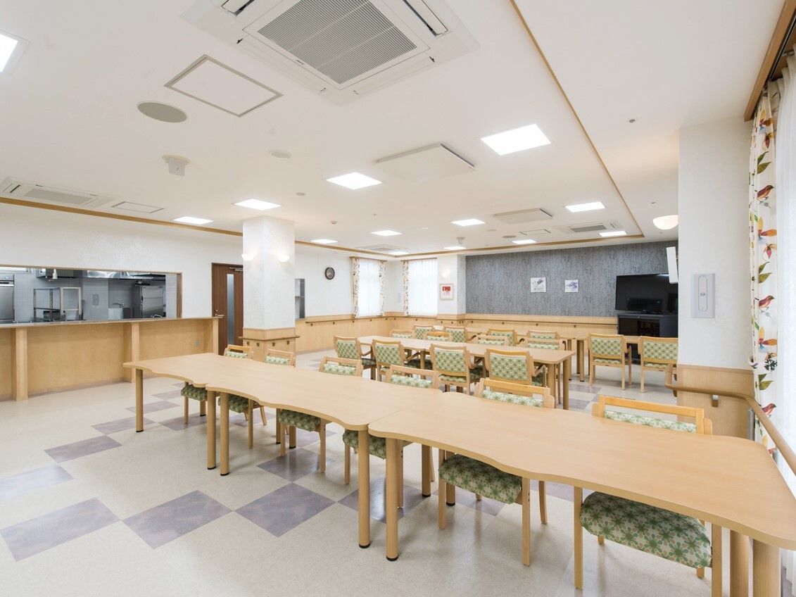 木製のダイニングテーブルセットが複数置かれた食堂のすぐそばに厨房があり、厨房内を見ることができる。