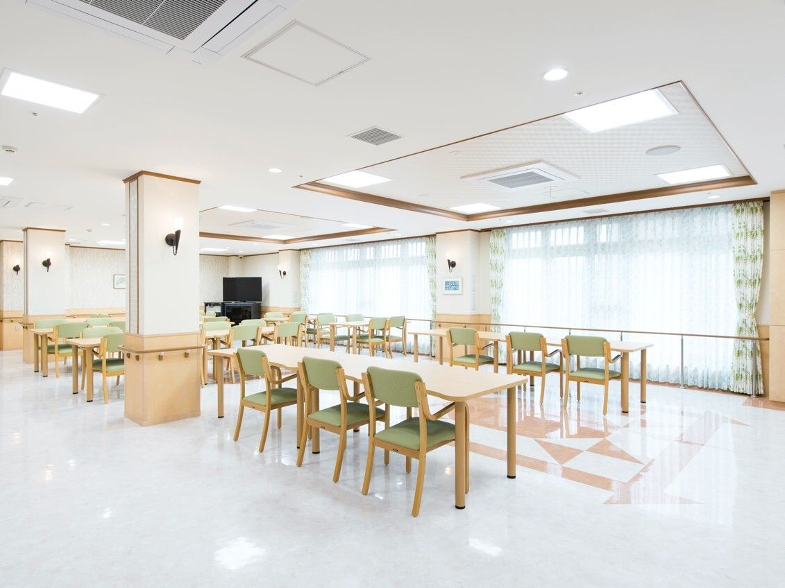 大きな窓が付いた食堂にはグリーンの椅子がセットされた木製のテーブルが複数並んでいる。