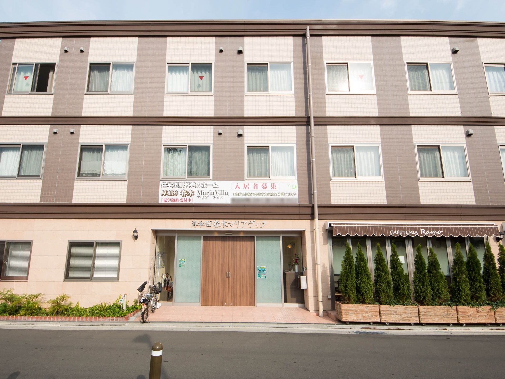 3階建てのツートンカラーが印象的な外観。ガラス窓の前には、背の高い植木を配置して生垣のようにしている。