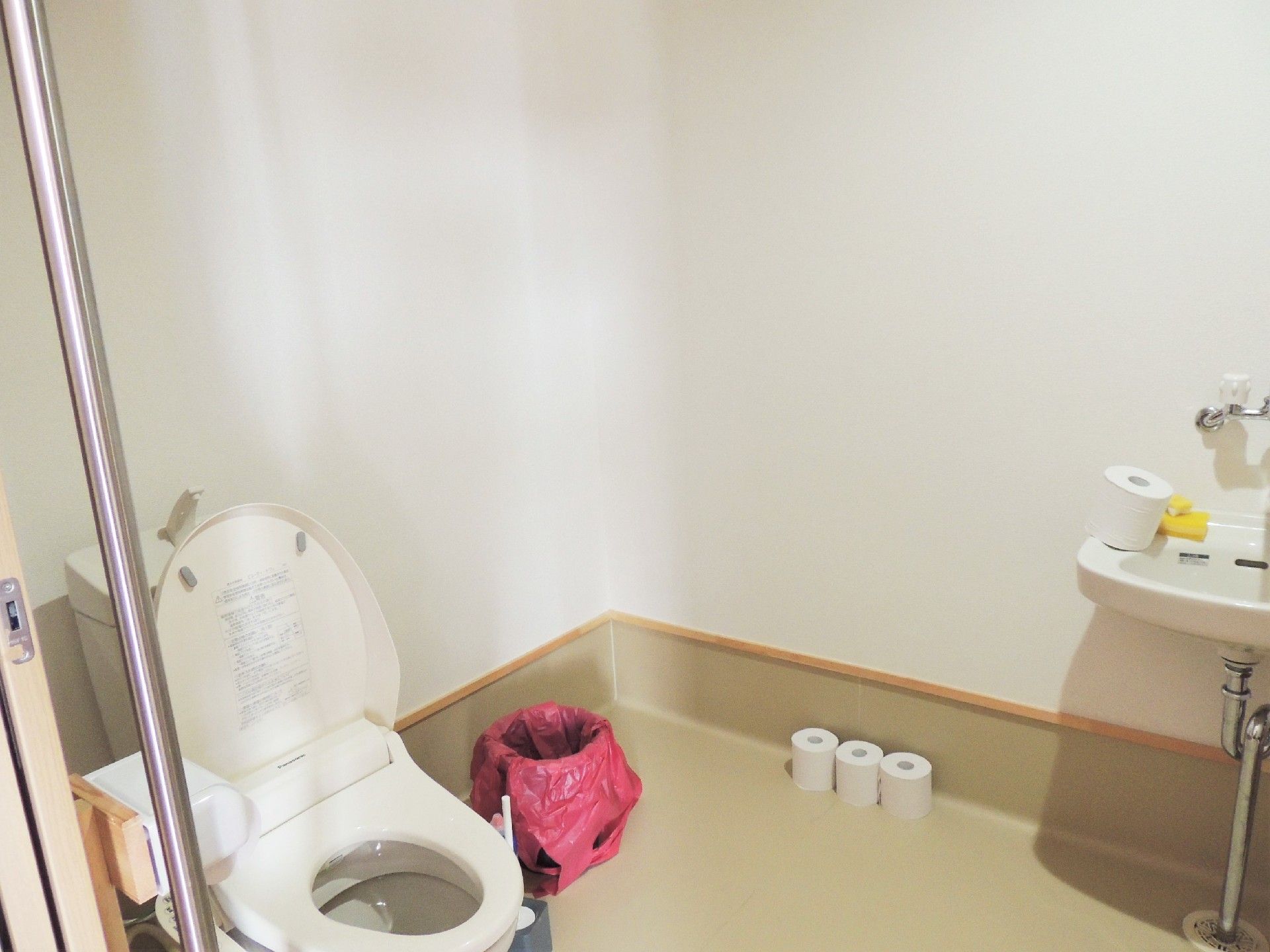 施設内の広めのトイレの様子。左側に便器、右側に洗面台がある様子