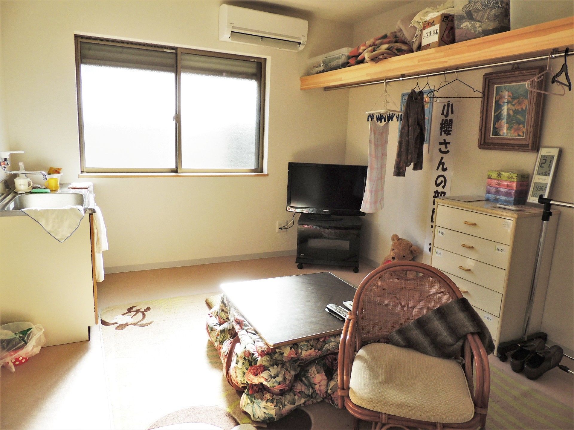施設内のワンルームタイプの部屋内を写した写真。左側にキッチンのシンク、右側に調度品が並べられている