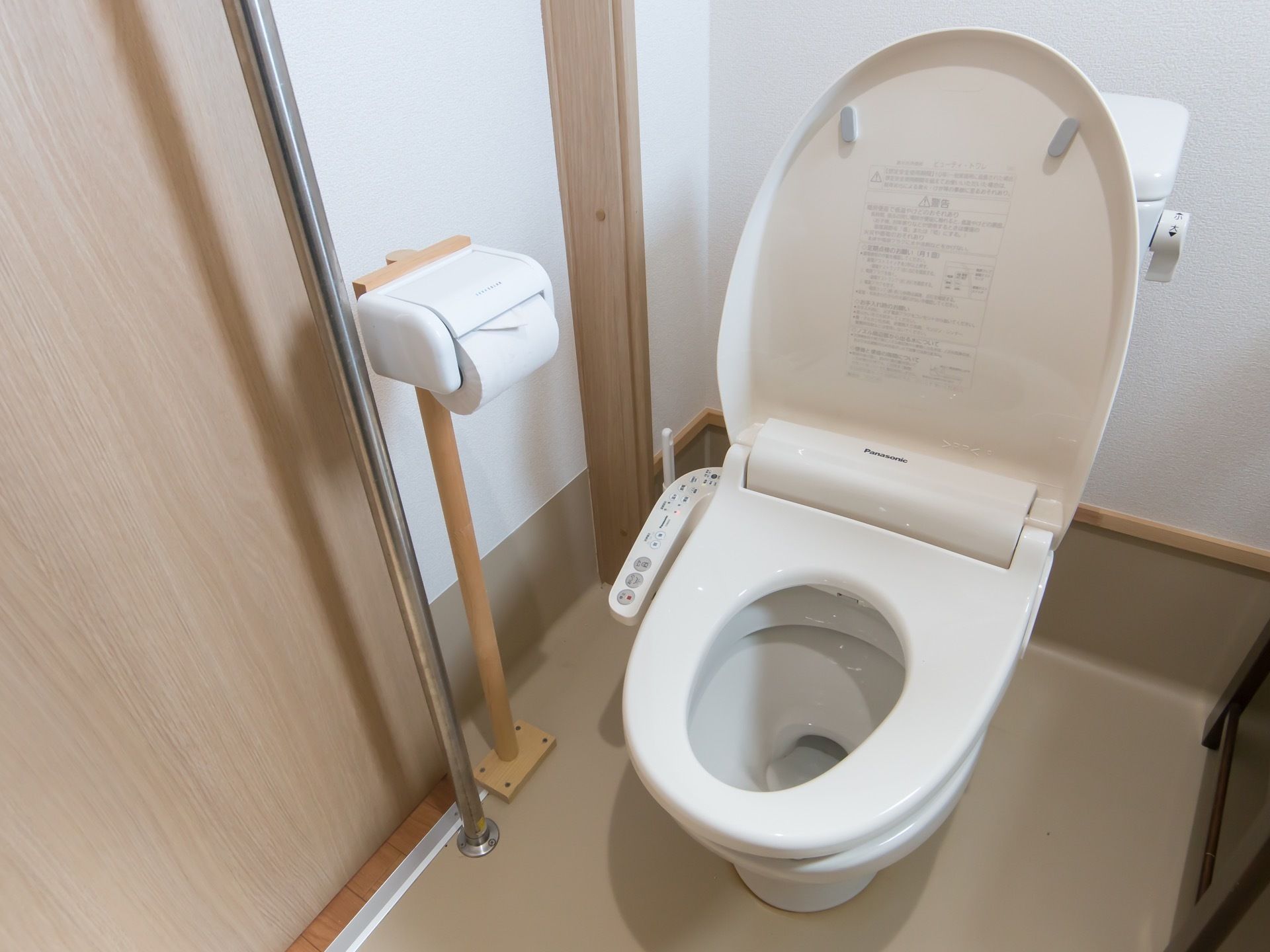 トイレには温水洗浄便座が設置されている。便器の横には木製のポールが立てられており、トイレットペーパーホルダーが付けられている。