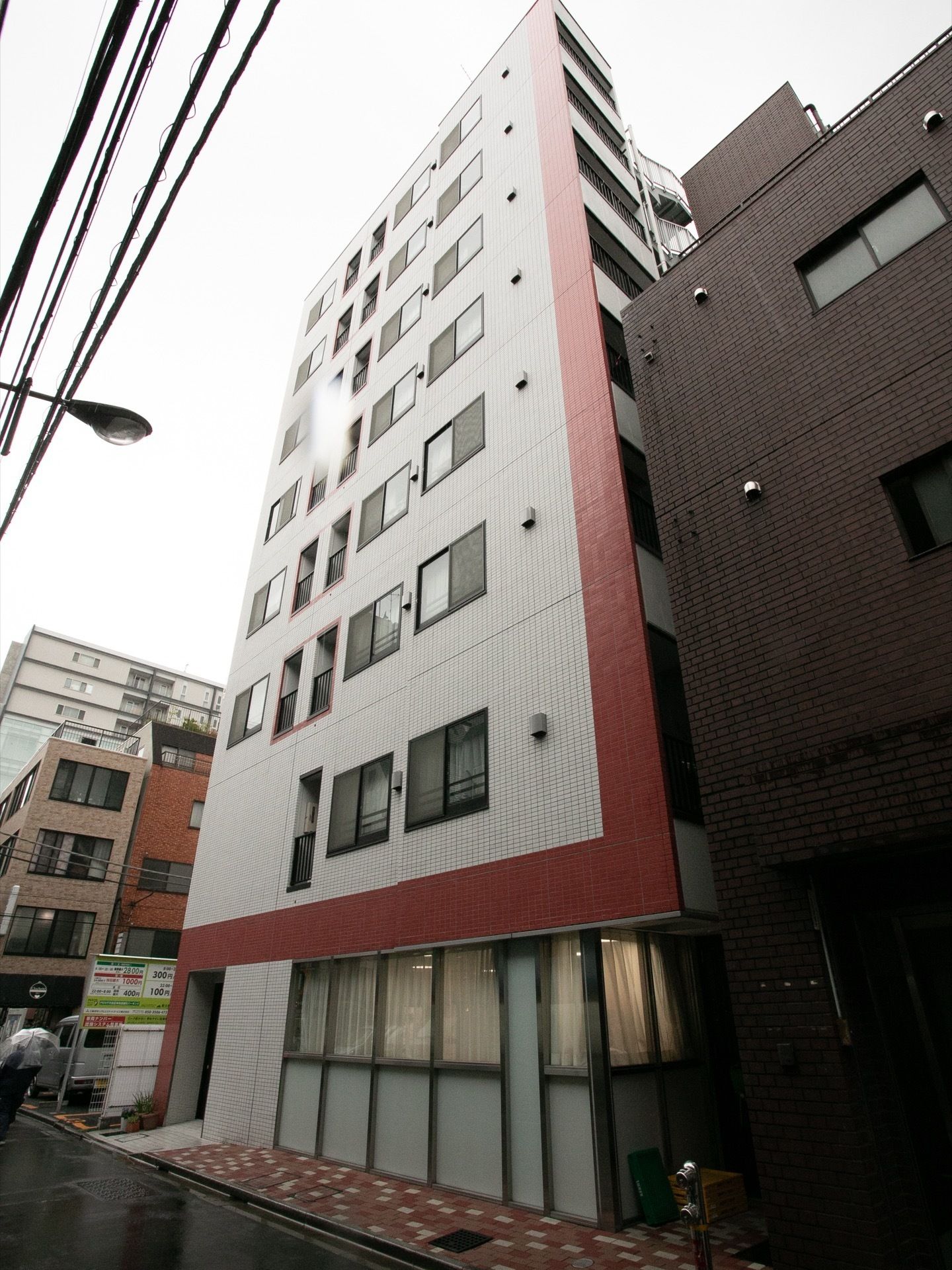 ベージュ色にブラウン色の囲みがある８階建ての建物である。建物の周りにはタイルが敷かれた歩道が設置されている。