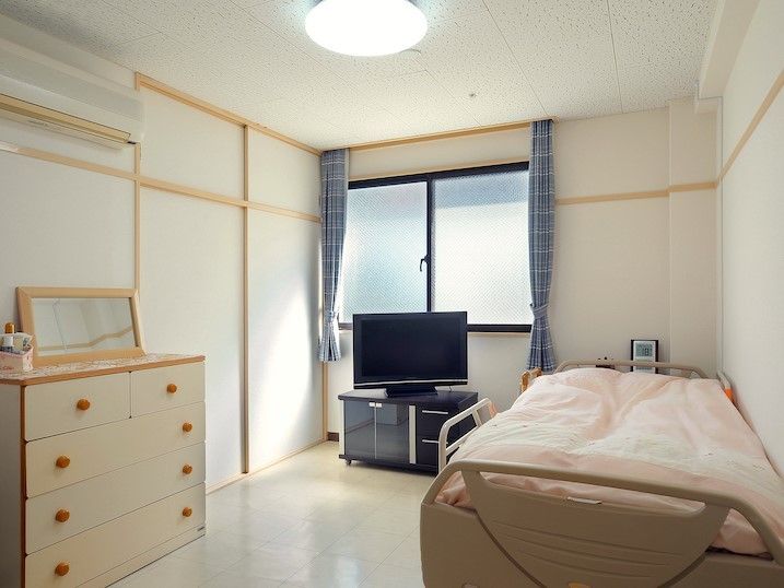 広めの個室内にタンスやベッドが並んでいる様子。テレビやテレビ台、エアコンもある