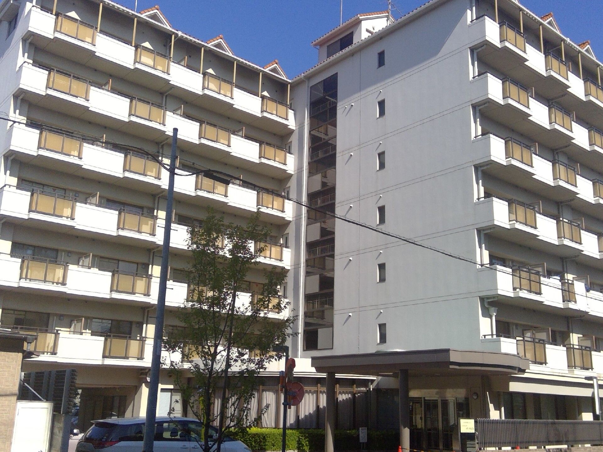 各フロアにベランダがあり、敷地内には駐車場があり、緑も植えられているマンションのような大きな白い建物。日当たりも良好。