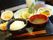 焼き魚にレモンが添えられ、白いご飯、味噌汁、かぼちゃの煮物、野菜の和え物などが並んでいる。