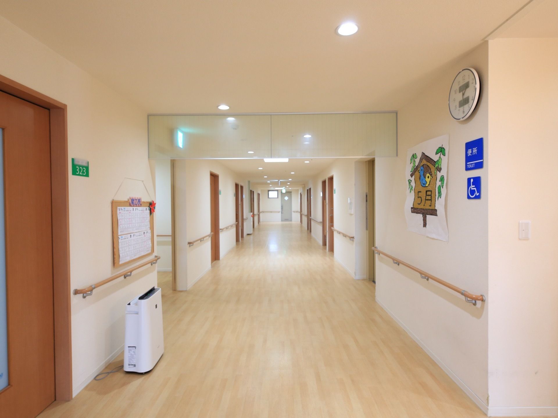 廊下には居室ドアが並んでいる。各部屋の前には、緑地に白字で部屋番号の書かれたプレートが取りつけられている。