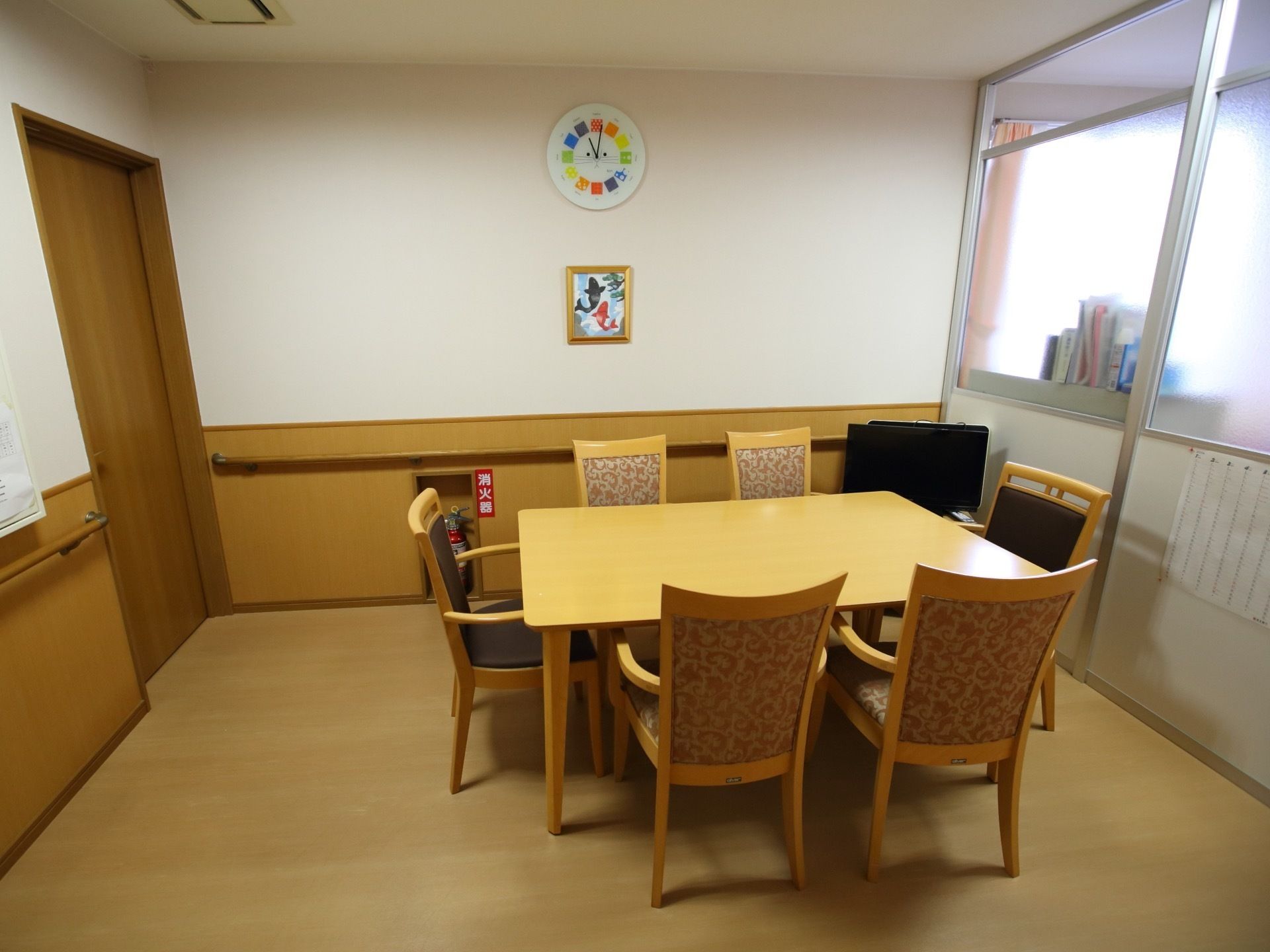 個室の面談室である。テーブルと椅子が用意されている。室内には手すりが設けられており、消火器が設置されている。