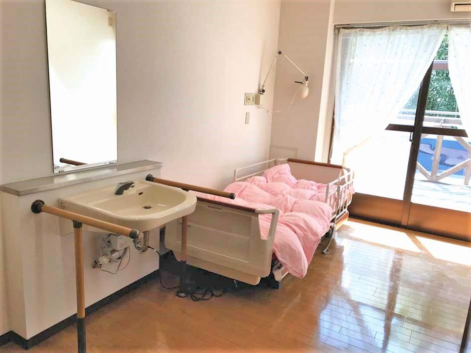 居室には大きな窓が付き、外にはベランダもある。布団付きのベッドや洗面所が付いている。