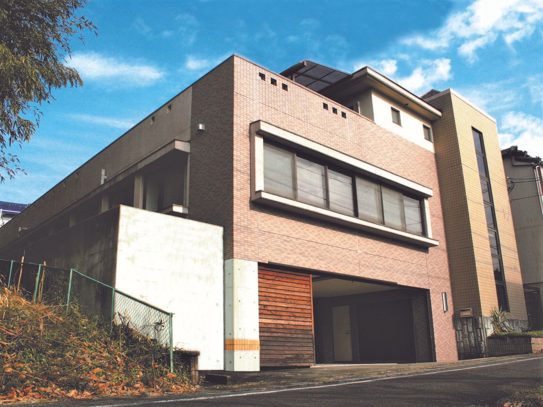 ブラウンを基調とした2階建ての建物。１階部分に駐車場があり、すっきりとした印象。