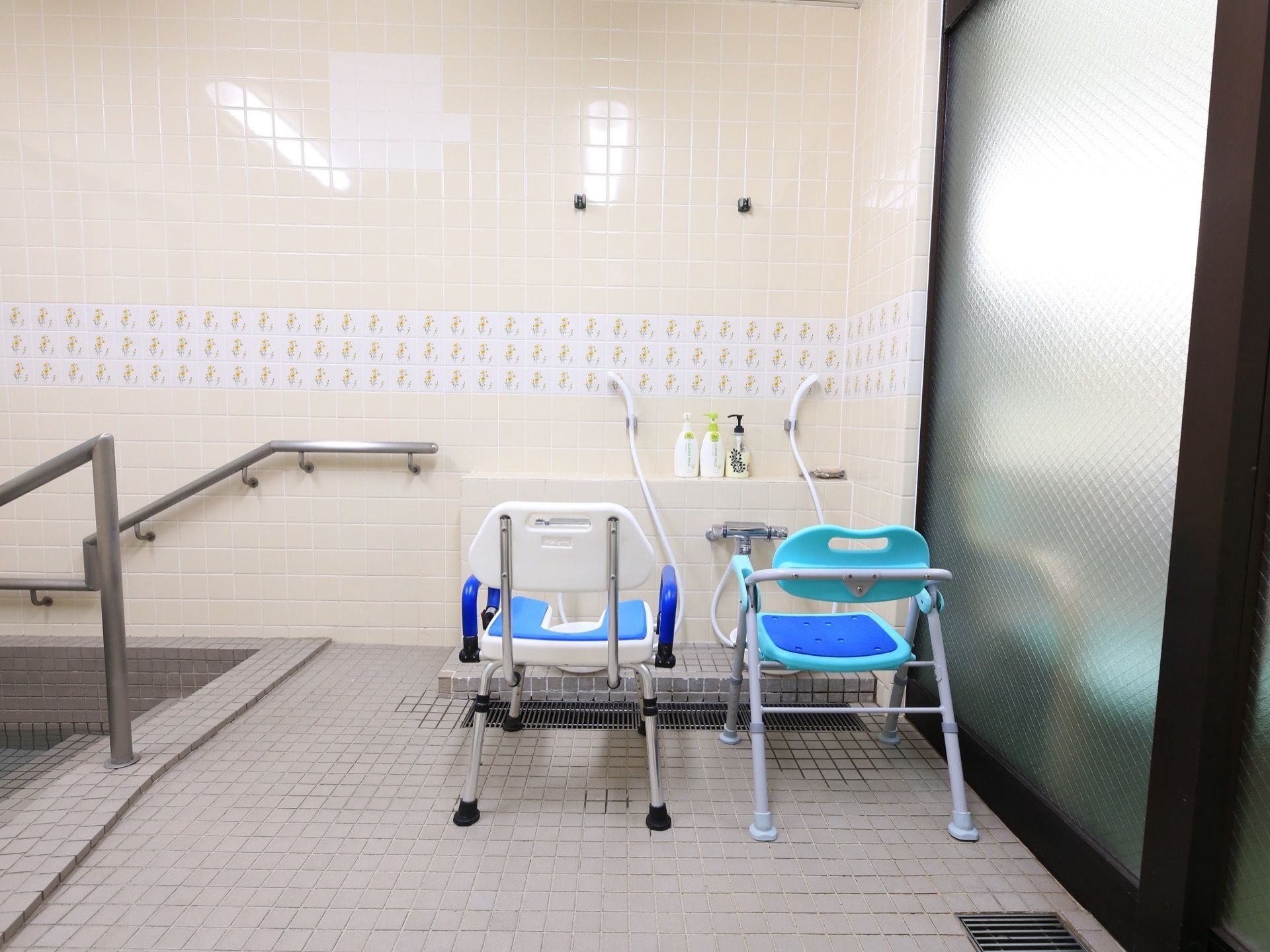 共同浴室の入口近くに洗い場が２か所あり、滑り止めがついた椅子が２つ並べられている。浴槽に入る所には手すりがある。