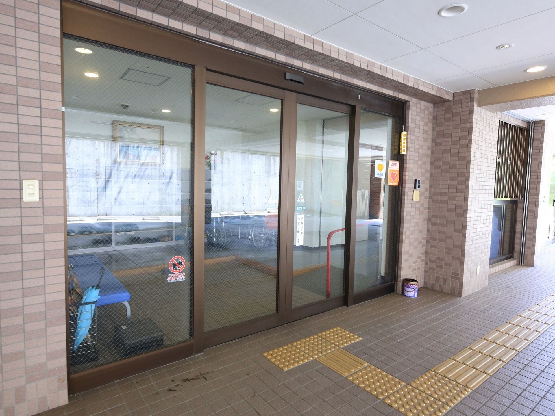 玄関は茶色の枠の大きなガラスの自動扉になっている。玄関前には大きなひさしがあり、床面には点字ブロックが敷かれている。