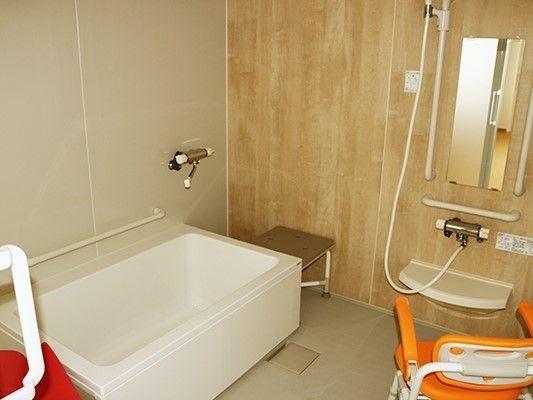 白い浴槽が置かれた広い浴室は洗い場がゆったりとしていて、シャワーや手すりも設置されている。