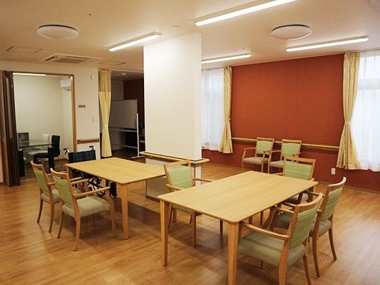 大きな窓には黄色のカーテンがつき、ダイニングテーブルが２つ、奥には部屋もある。