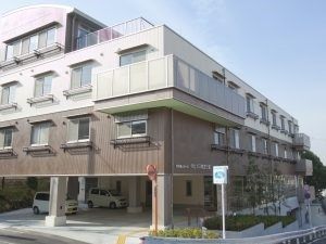 ４階建ての建物の１階部分は駐車場となっていて、２階部分はブラウン、それより上の階が白い外壁。
